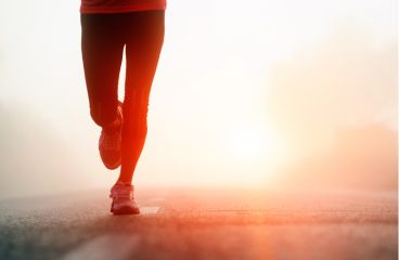 Runners legs on the road with a red sunset behind